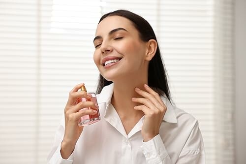 Femme souriante appliquant du parfum